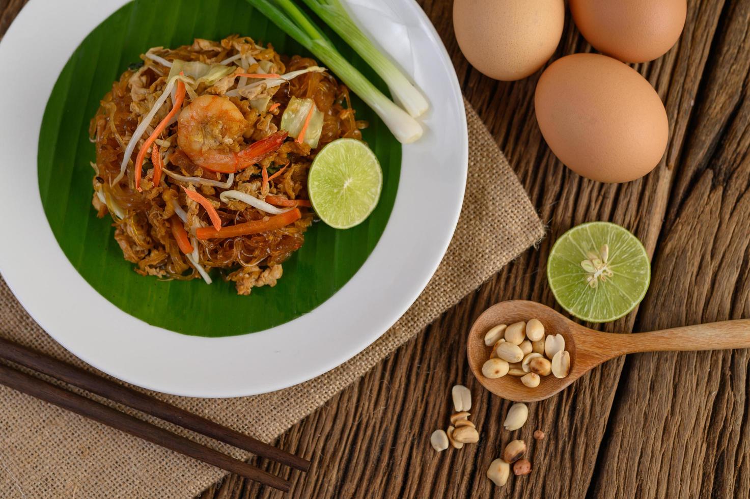plato de pad thai camarones con limón y huevos foto