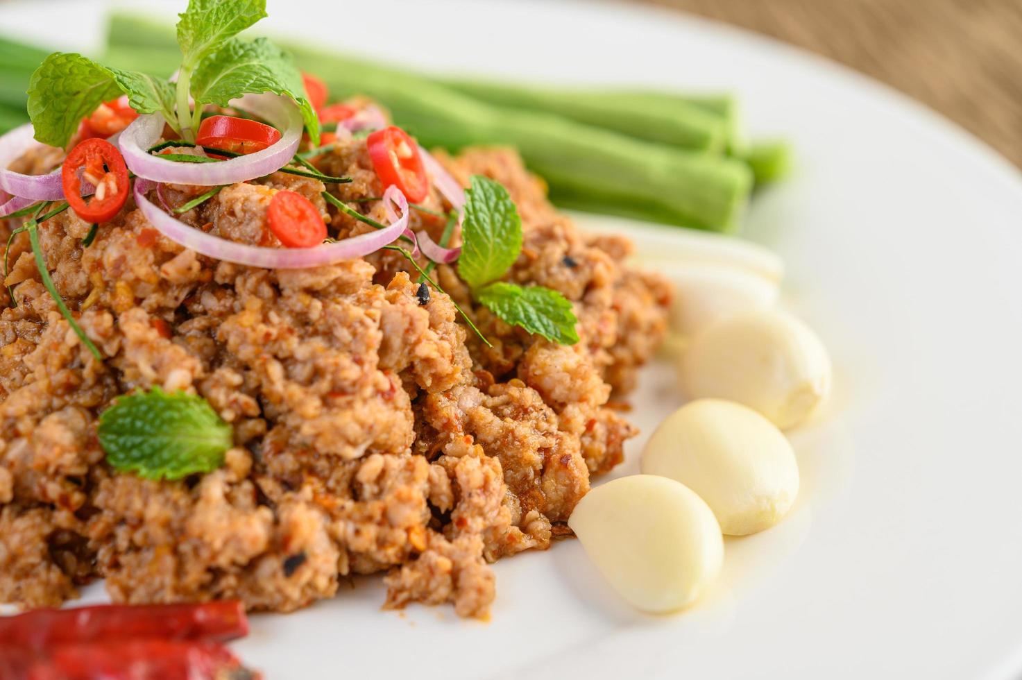 Spicy minced pork salad on green vegetables photo