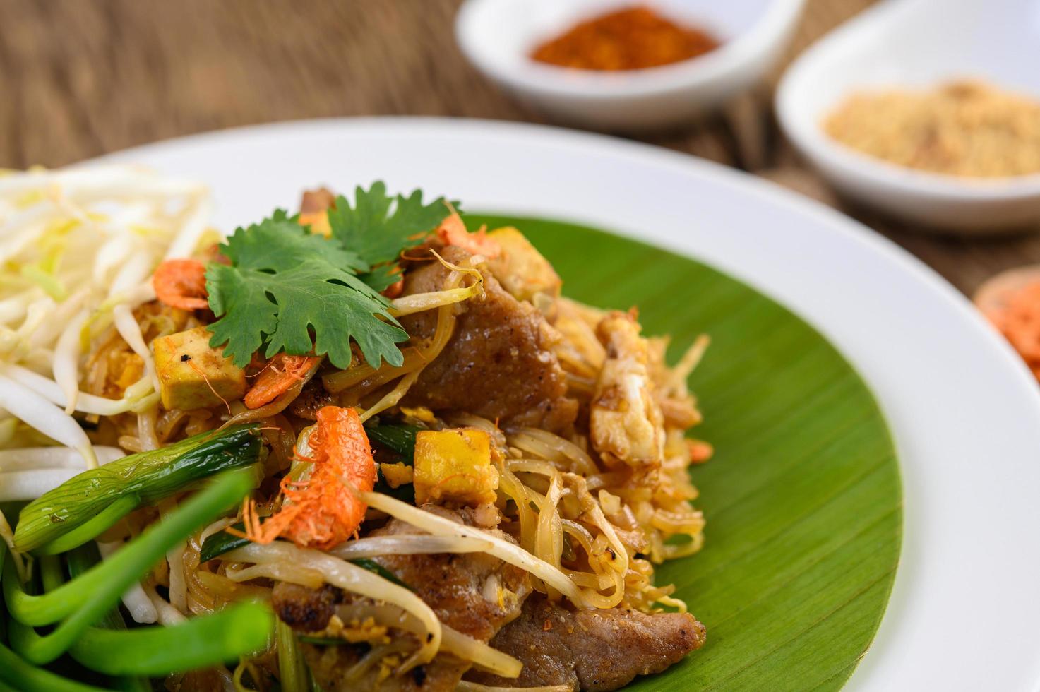 Pad Thai with lemon, eggs and seasoning on a wooden table photo