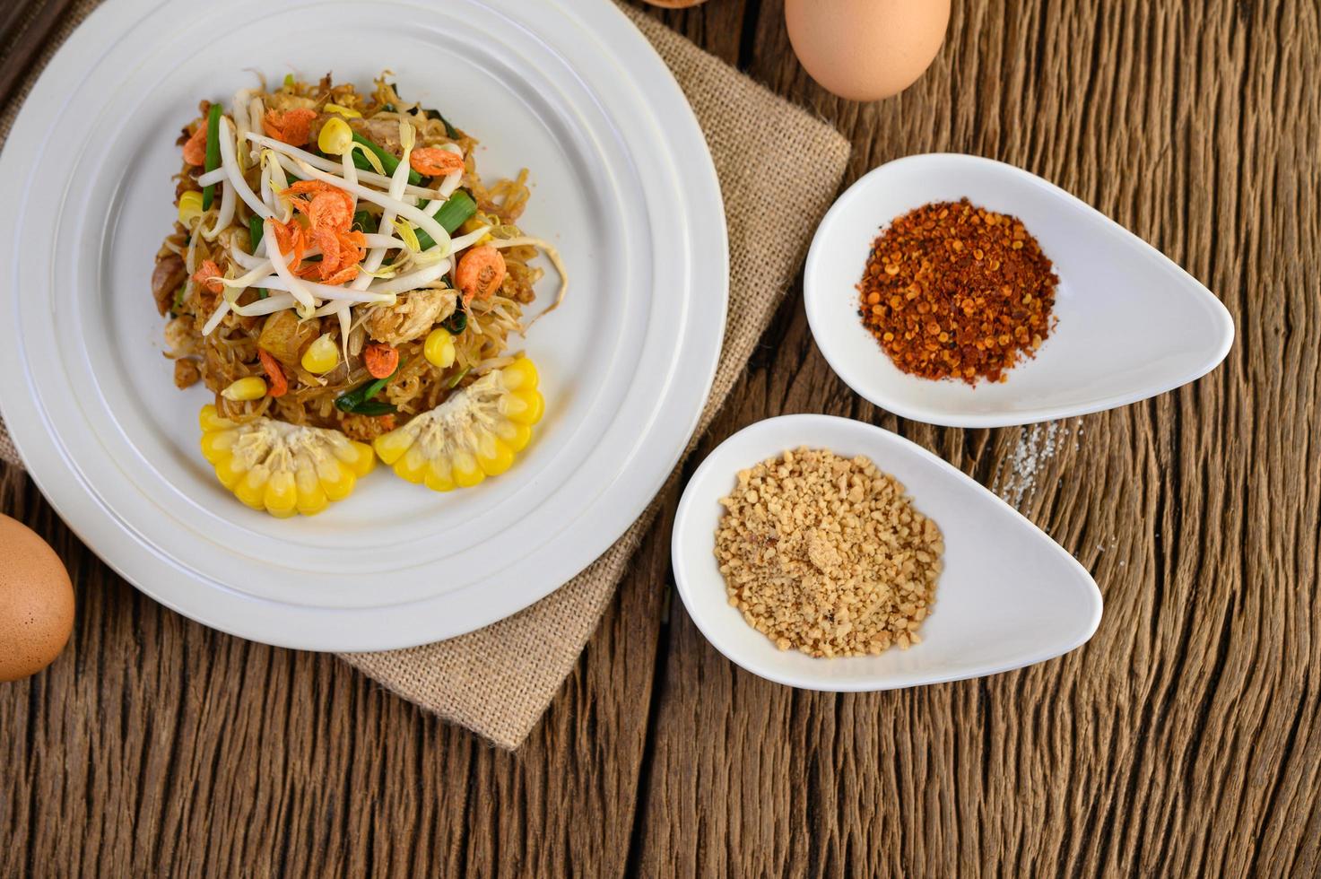 Pad Thai with lemon, eggs and seasoning on a wooden table photo