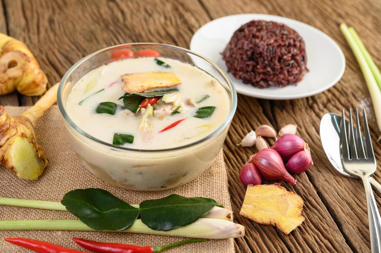 tom kha kai, sopa de coco tailandesa sobre tabla de cocina de madera foto