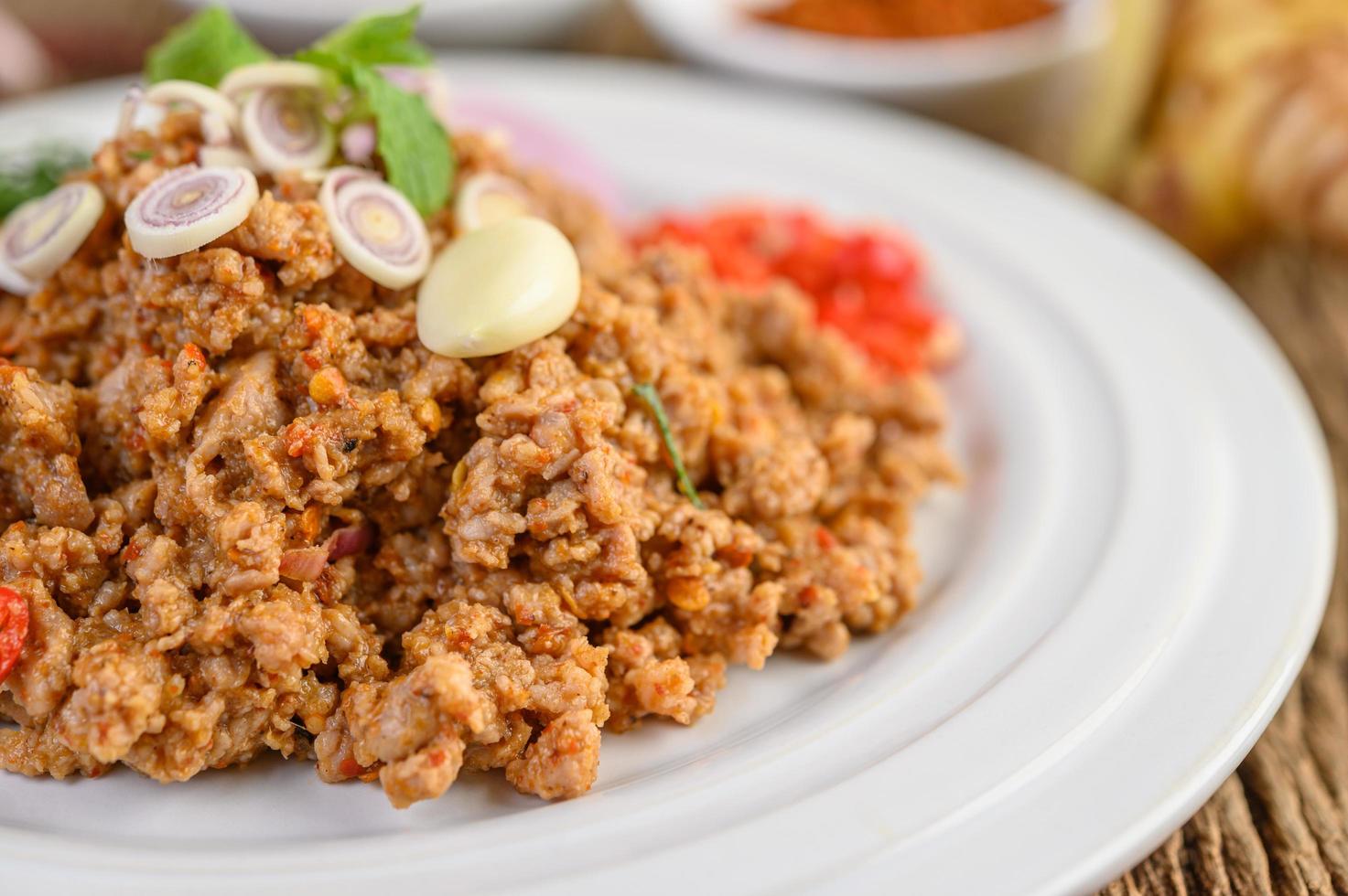 Ensalada de cerdo picada con especias sobre una mesa de madera foto