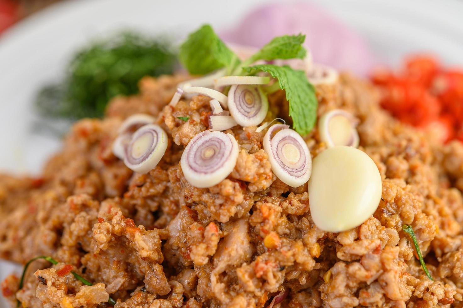 Ensalada de cerdo picada con especias sobre una mesa de madera foto