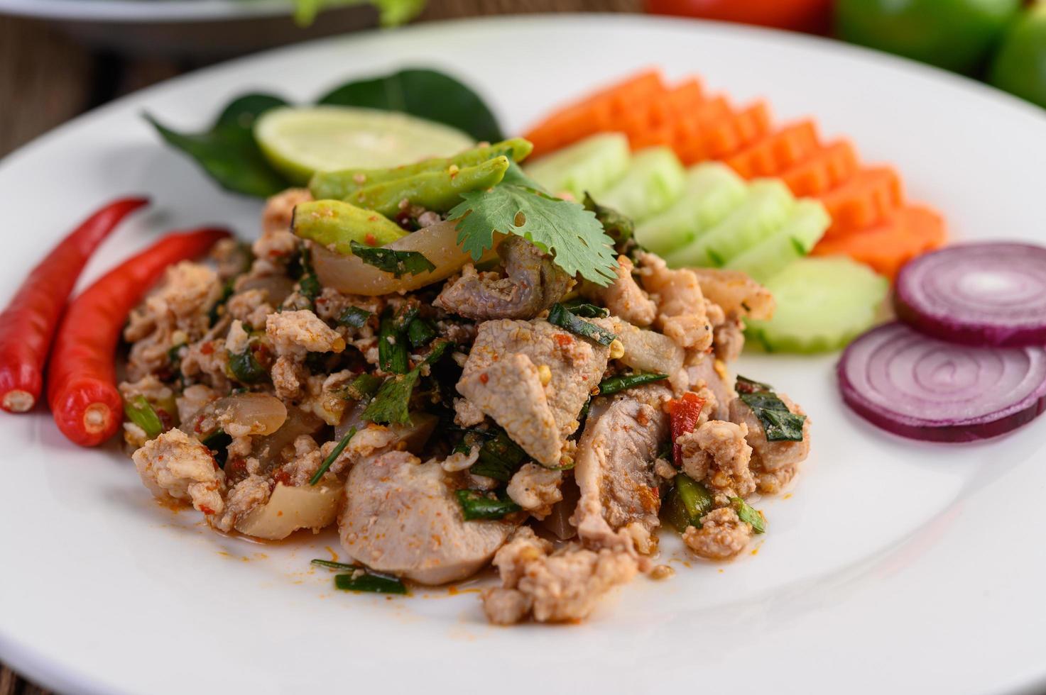 Ensalada de cerdo picada con especias sobre una mesa de madera foto