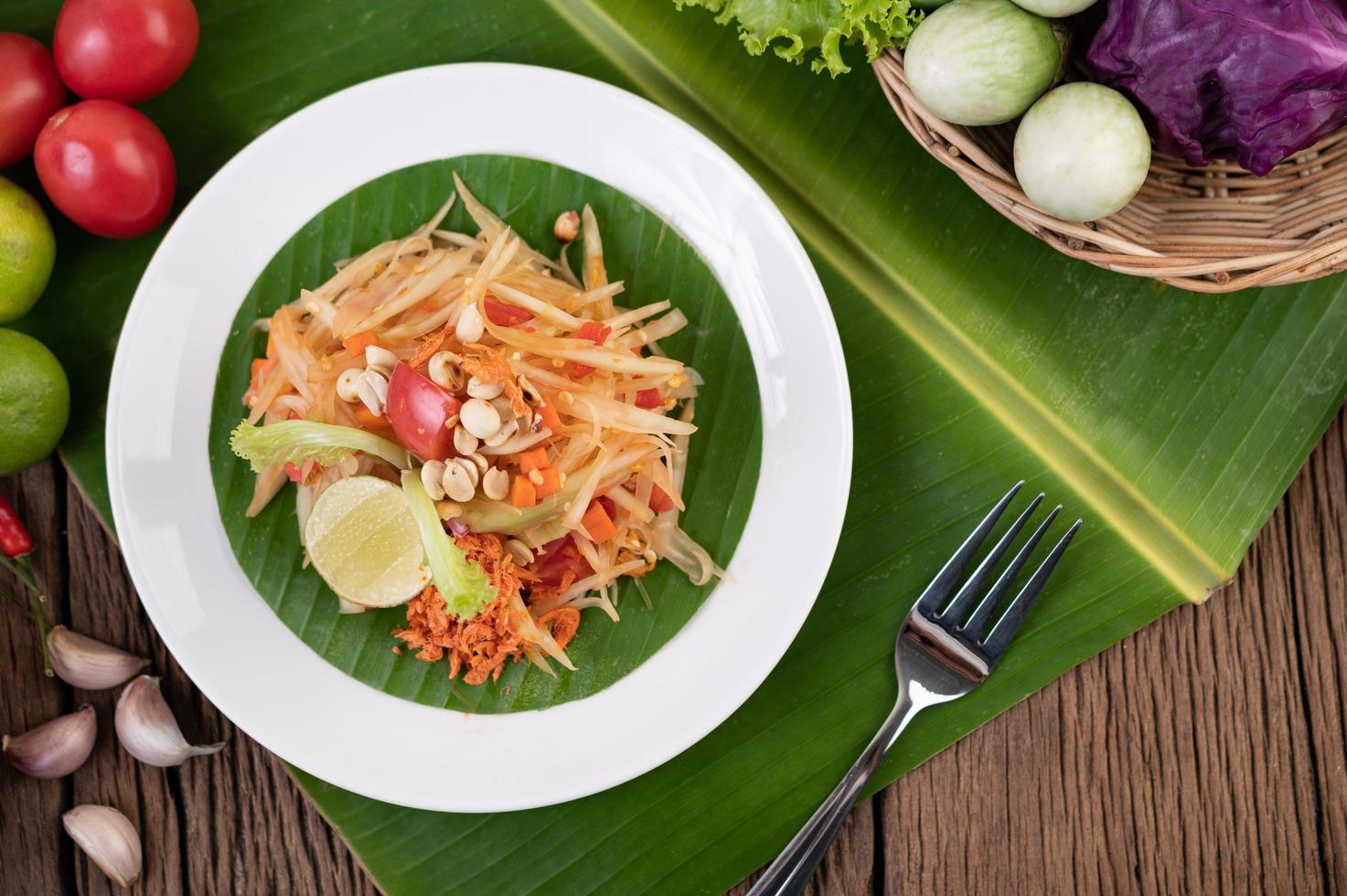 Ensalada tailandesa de papaya con hojas de plátano e ingredientes frescos foto