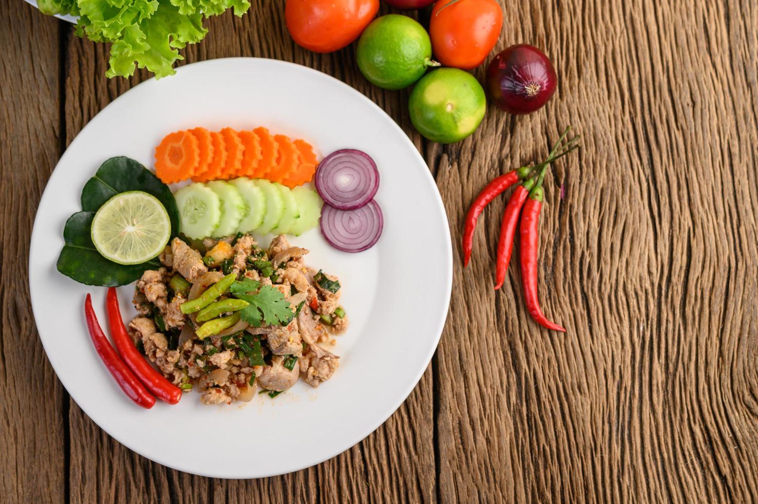 Ensalada de cerdo picada con especias sobre una mesa de madera foto