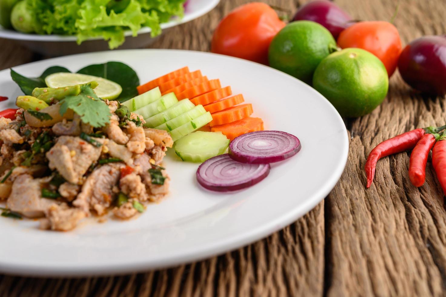 Ensalada de cerdo picada con especias sobre una mesa de madera foto