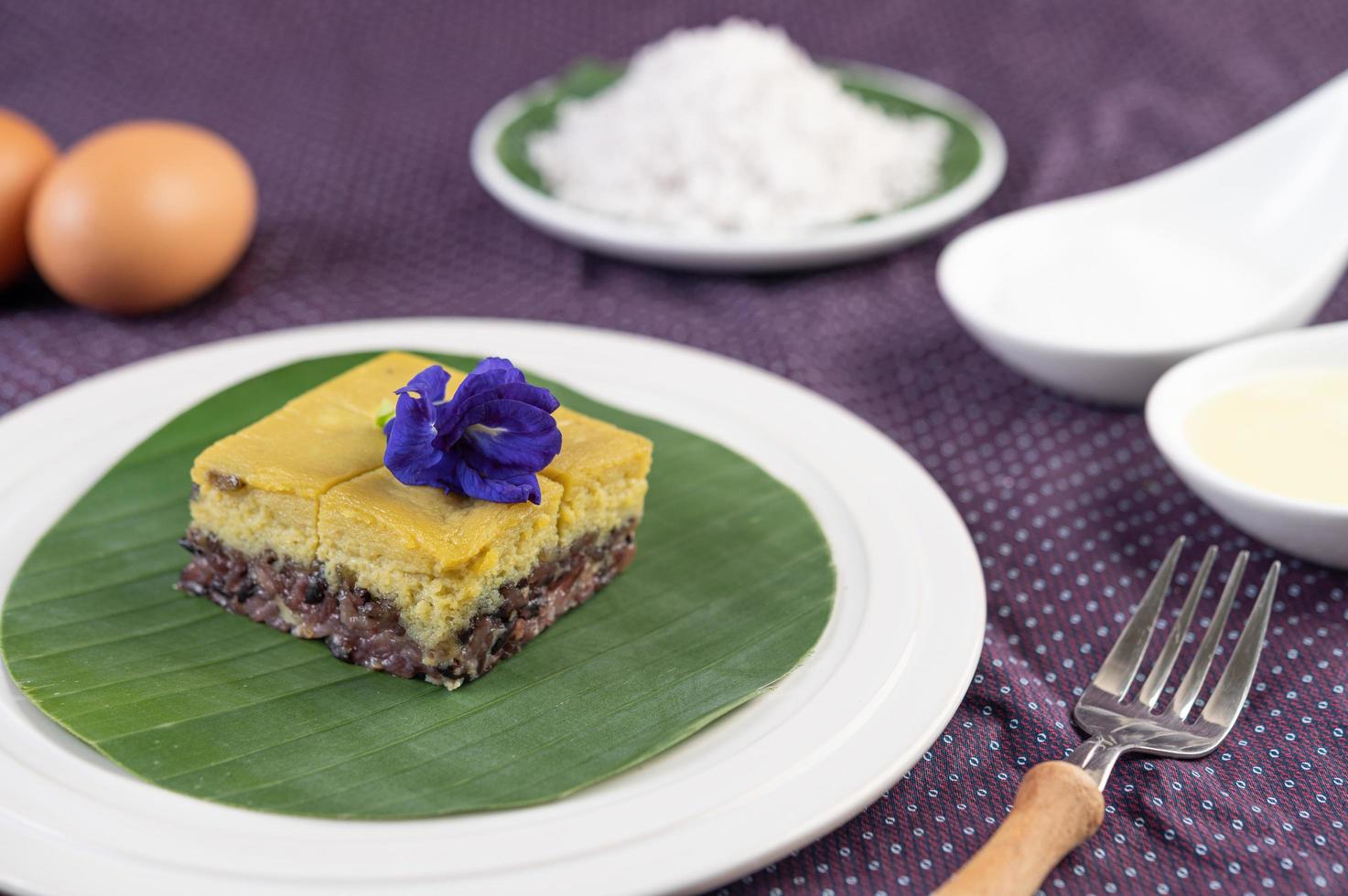 Arroz pegajoso negro sobre una hoja de plátano en un plato blanco con flores de guisantes de mariposa foto