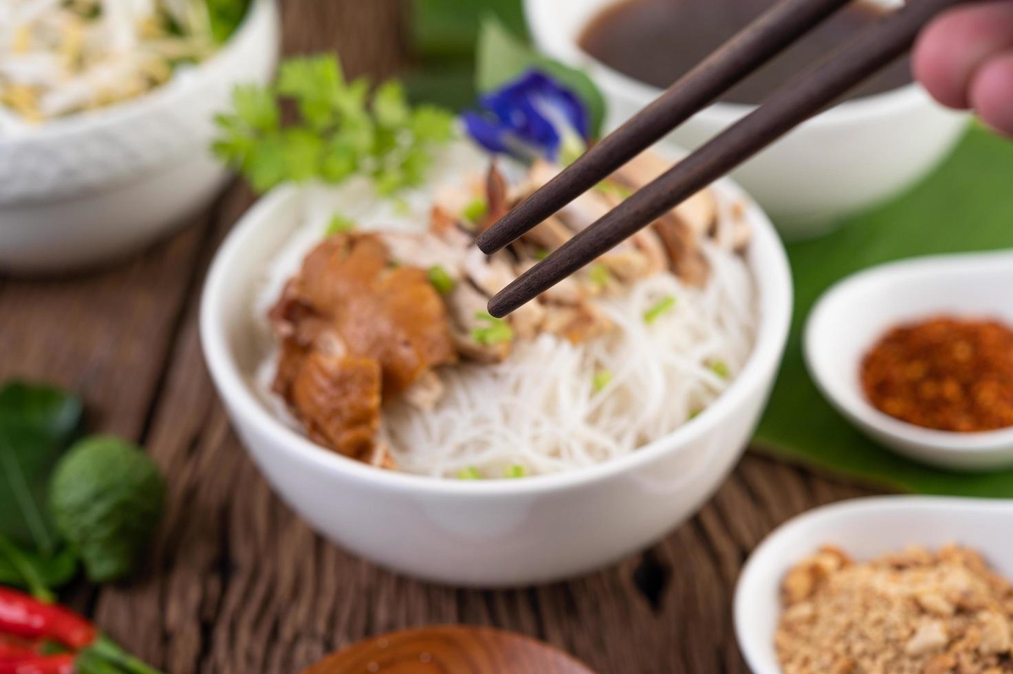 Chicken noodles in a bowl with Thai side dishes photo