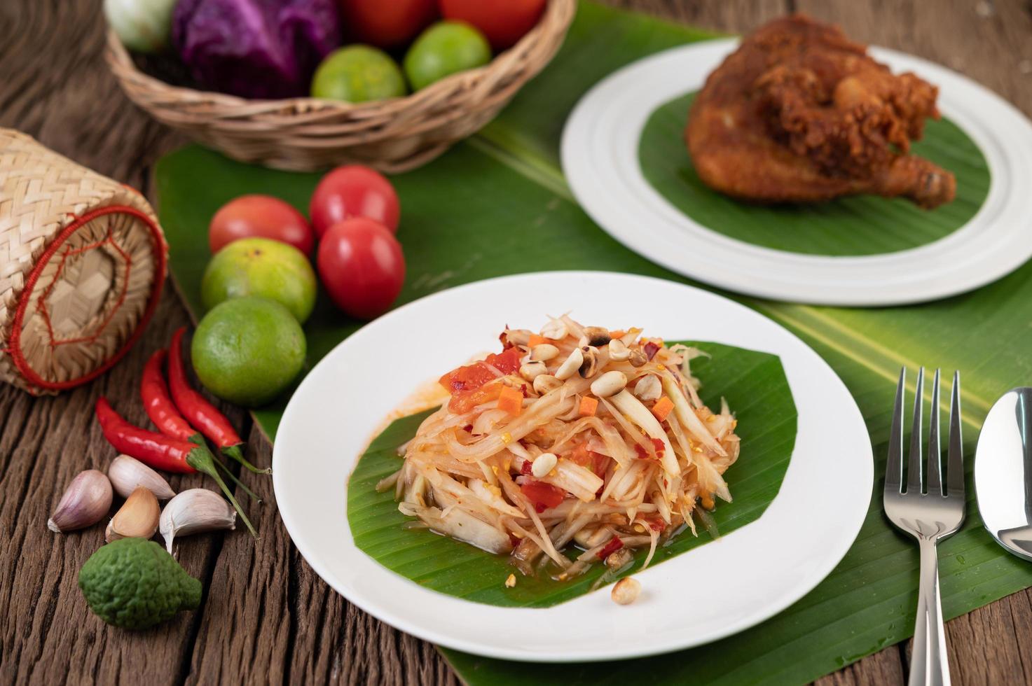 Ensalada tailandesa de papaya con hojas de plátano e ingredientes frescos foto