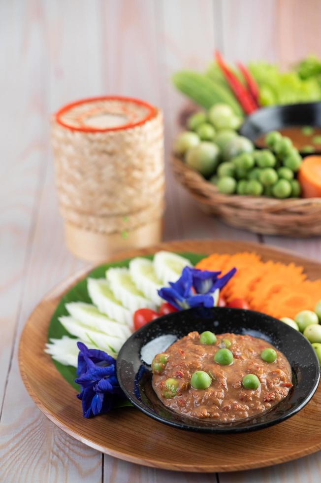 Chili paste paste in a bowl with eggplant, carrots, chili and cucumbers photo