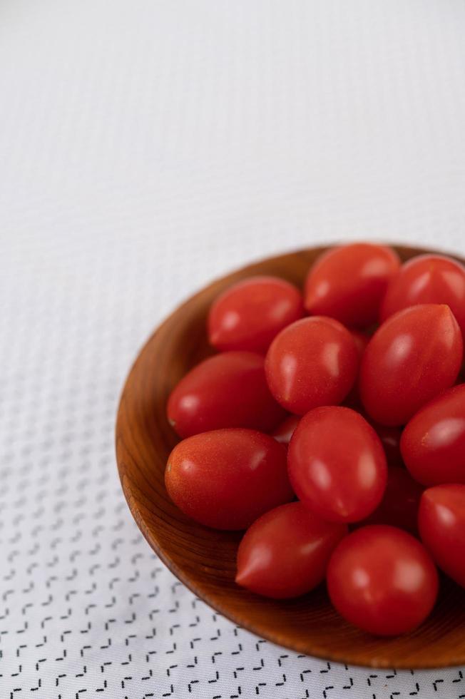 tomates en una taza de madera sobre un paño blanco foto