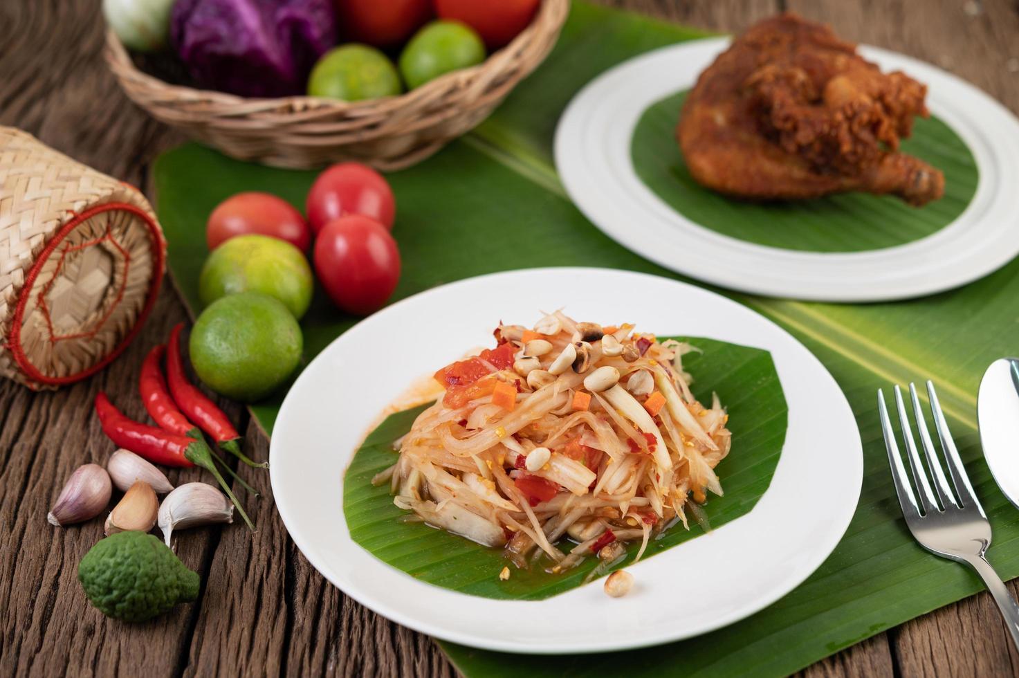 Ensalada tailandesa de papaya con hojas de plátano e ingredientes frescos foto