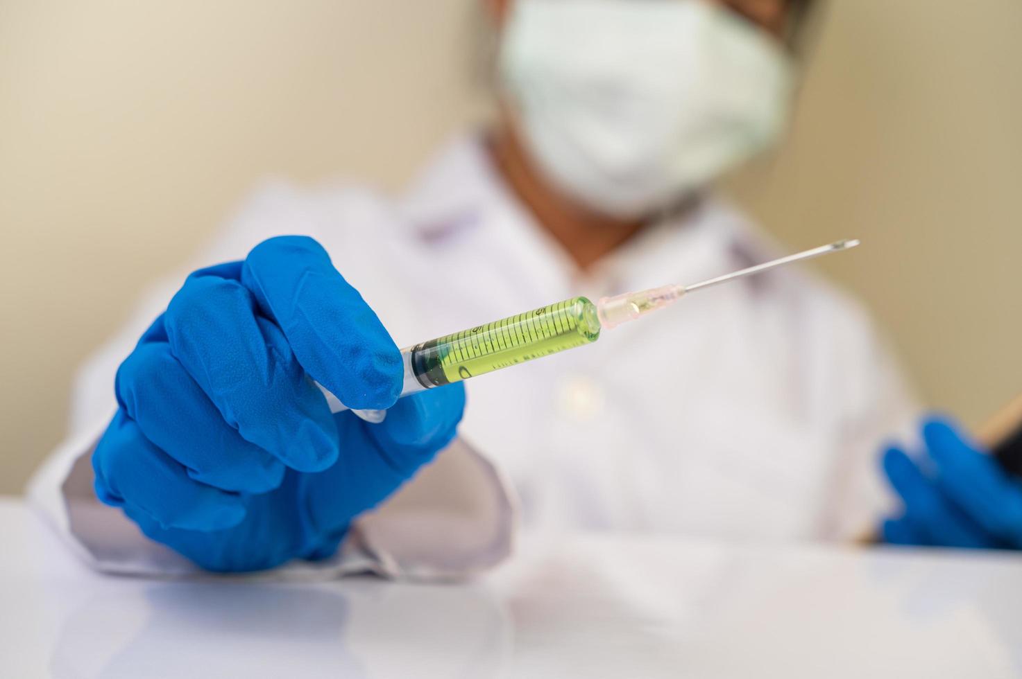 Scientists wearing masks and gloves holding a syringe with a covid-19 vaccine photo