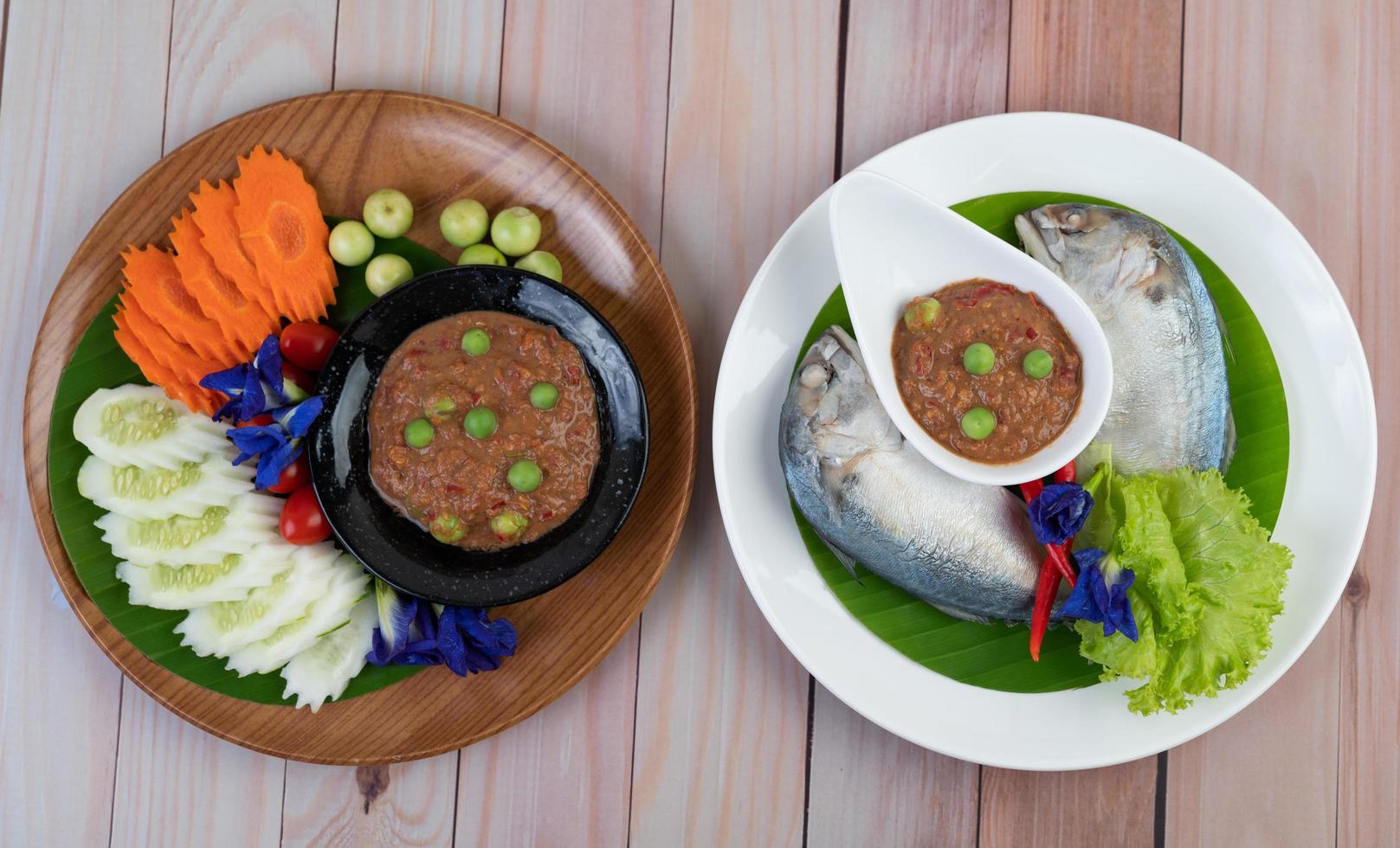 Chili paste in a bowl with mackerel and eggplant, carrots, peppers and cucumbers photo