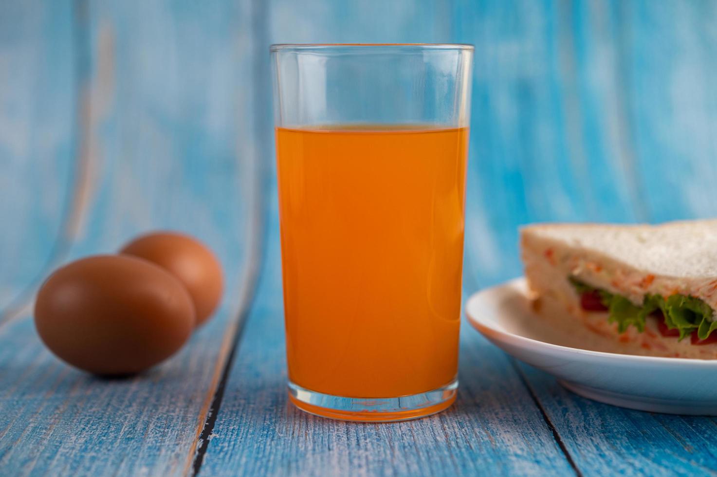 Sandwiches and orange juice on blue wooden table photo