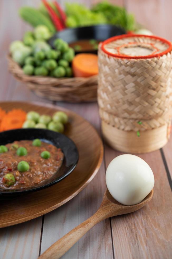 Chili paste paste in a bowl with eggplant, carrots, chili and cucumbers in a basket photo