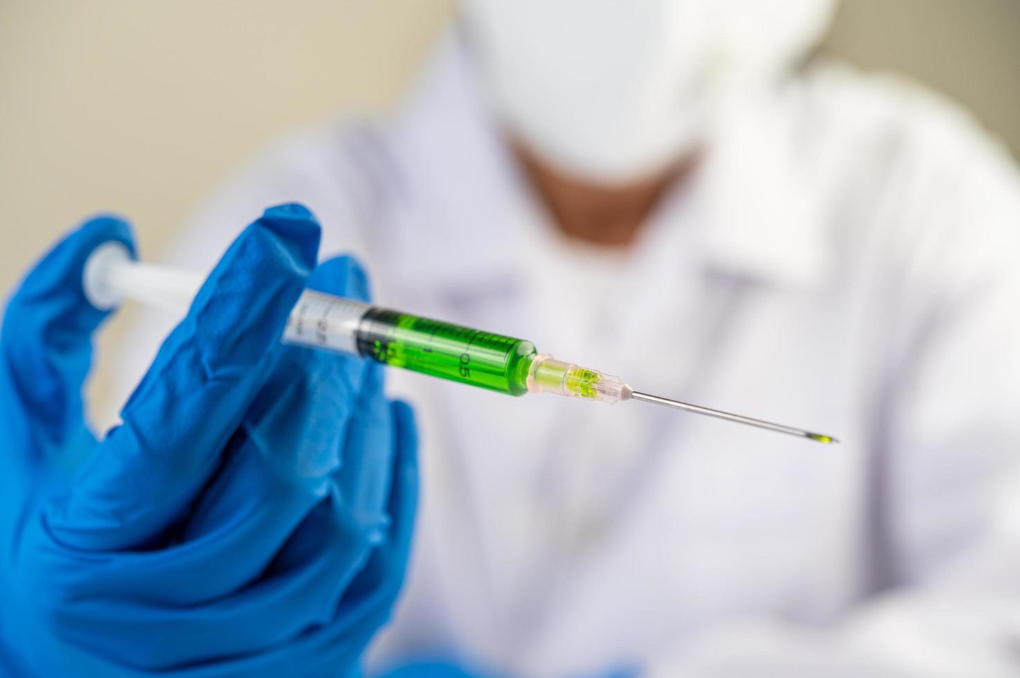 Scientist wearing masks and gloves holding a syringe with a covid-19 vaccine photo