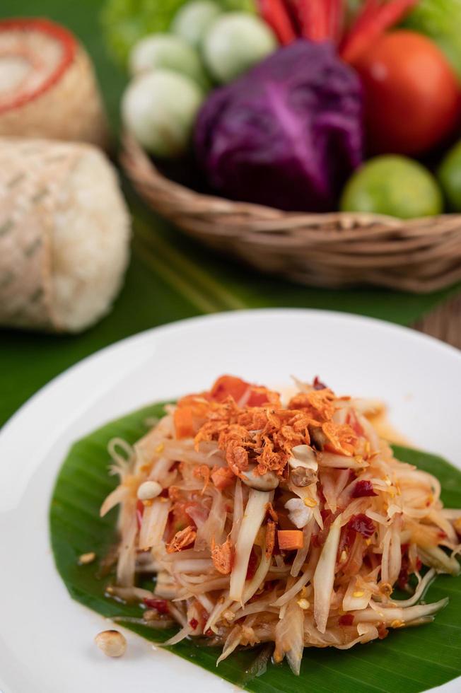 Ensalada tailandesa de papaya con hojas de plátano e ingredientes frescos foto