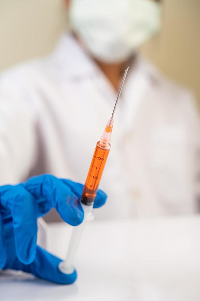 Scientists wearing masks and gloves holding a syringe with a covid-19 vaccine photo