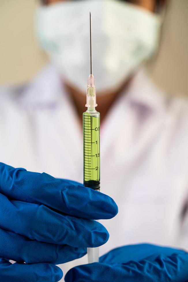 Scientist wearing masks and gloves holding a syringe with a covid-19 vaccine photo