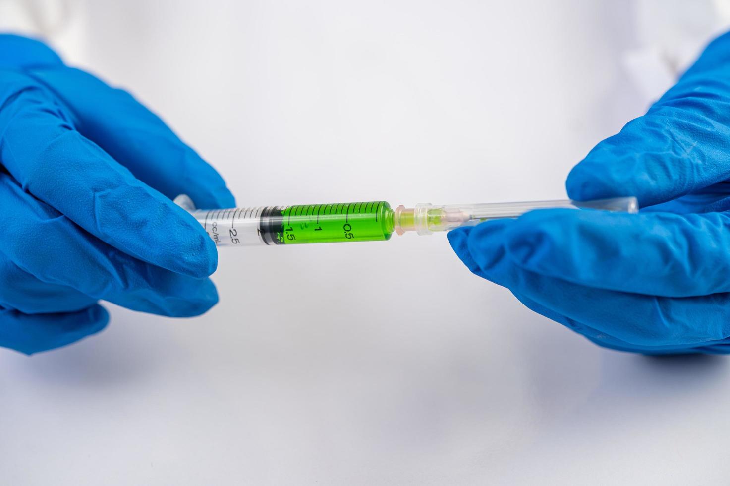 Scientist wearing gloves holding a syringe with a vaccine to prevent covid-19 photo