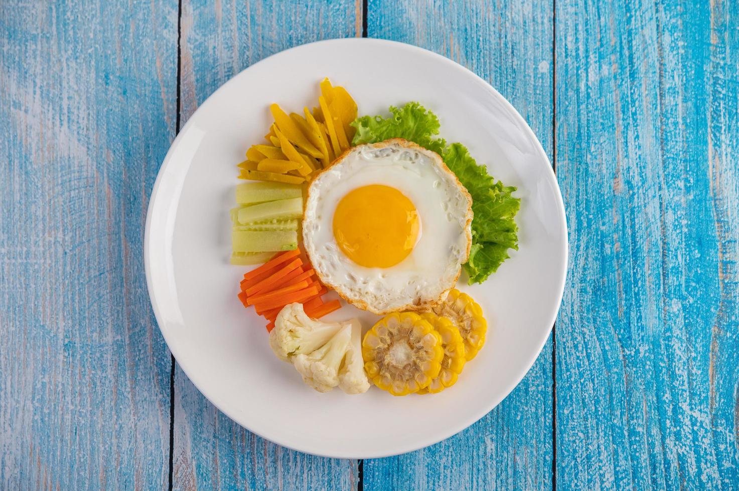 American fried egg with salad, pumpkin, cucumber, carrot, corn and cauliflower photo