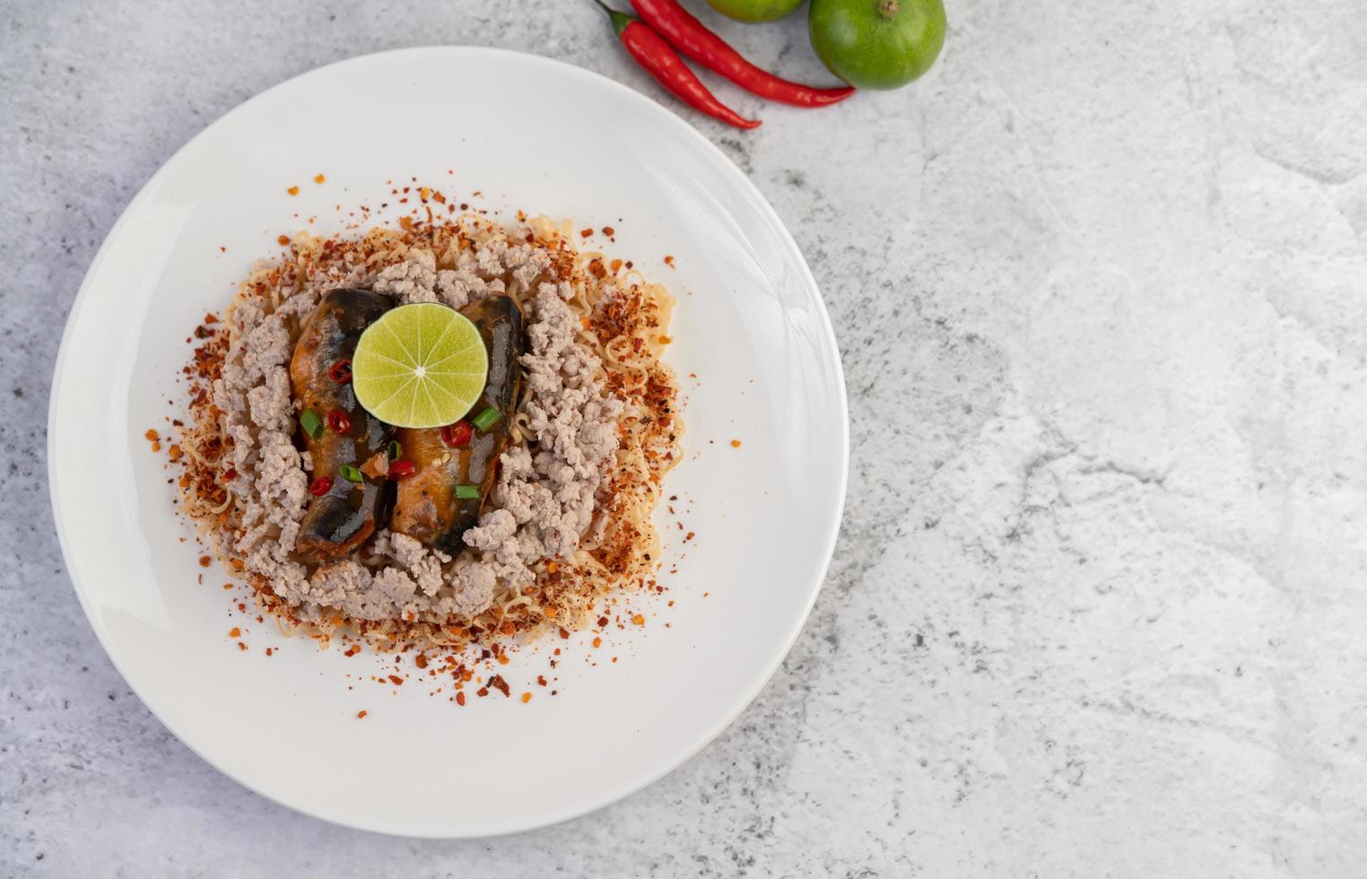 fideos cubiertos con carne de cerdo picada, pescado enlatado y limón foto