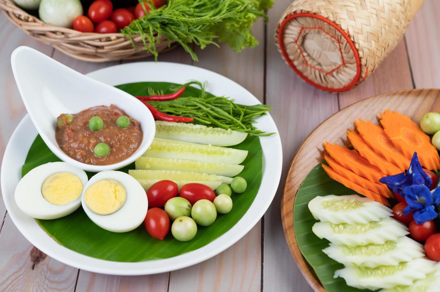 Chili paste paste in a bowl with eggplant, carrots, chili and cucumbers in a basket photo