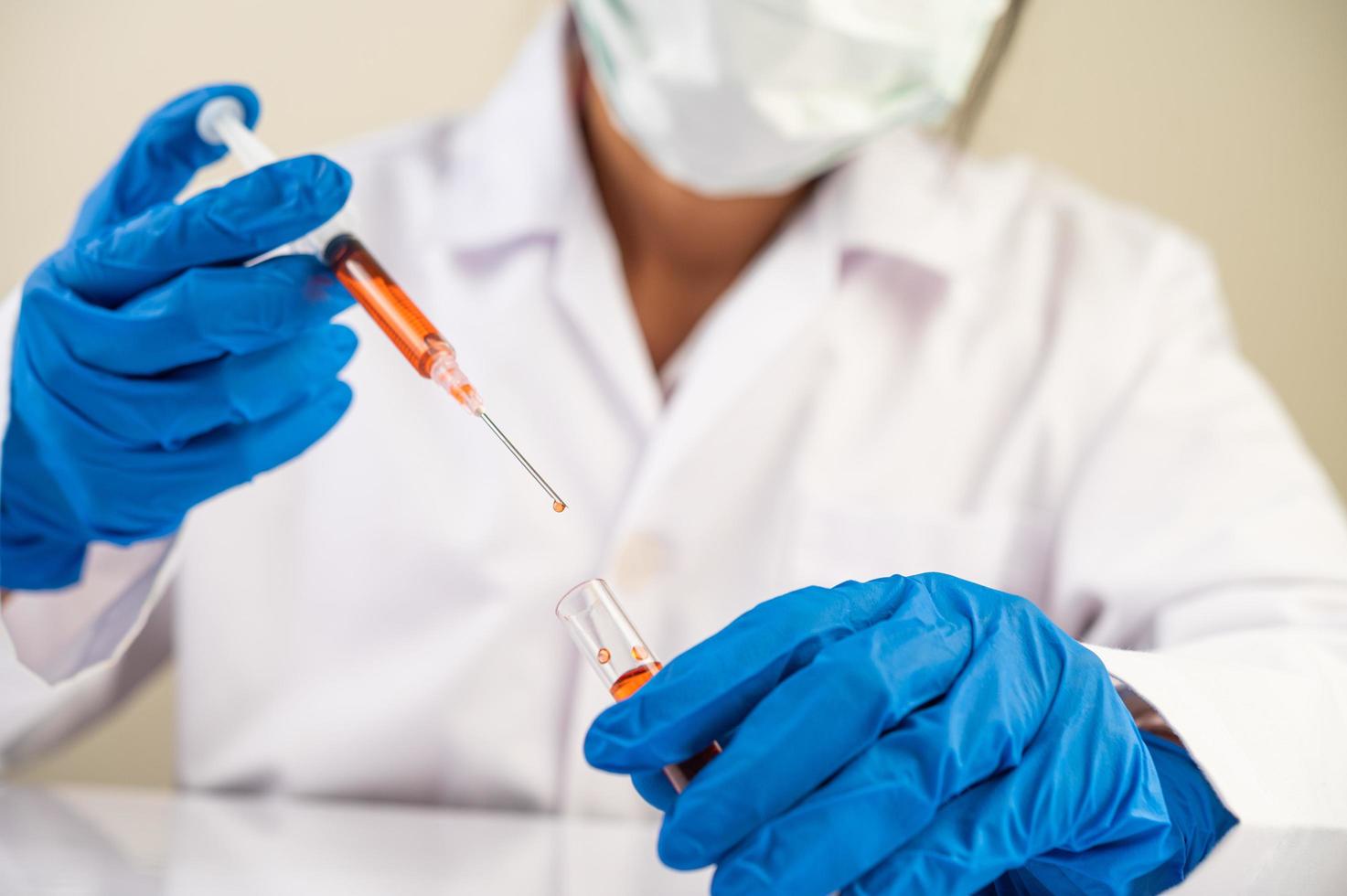 Scientists wearing masks and gloves holding a syringe with a covid-19 vaccine photo