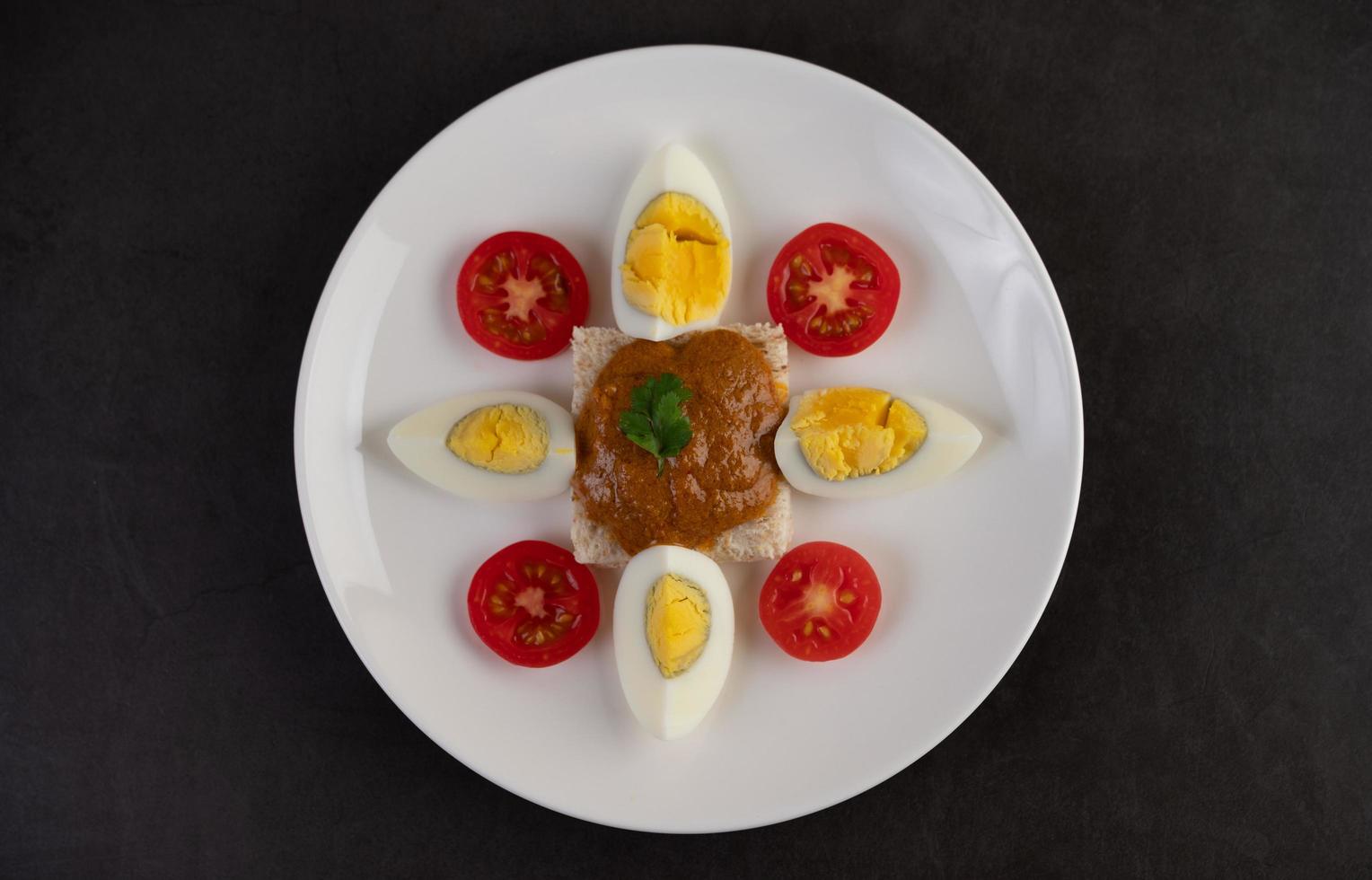 pan cubierto con pasta de chile con huevos cocidos y tomates foto