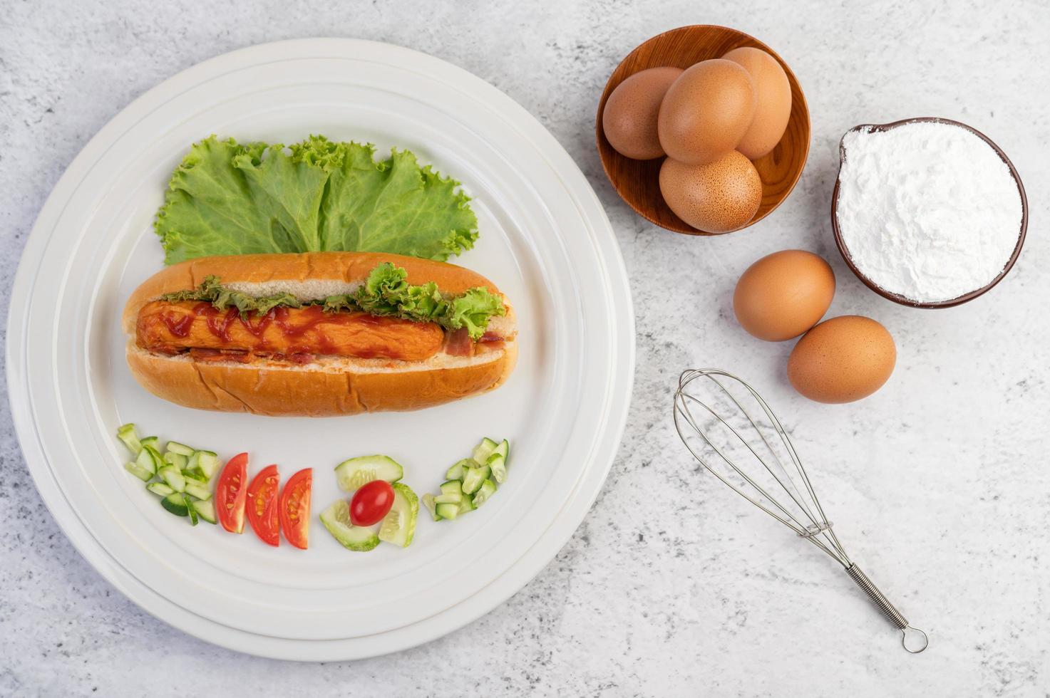 Sausage in bread and lettuce topped with sauce and eggs with flour photo