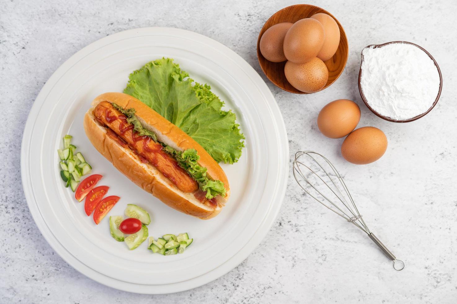 salchicha en pan y lechuga cubierta con salsa y huevos con harina foto