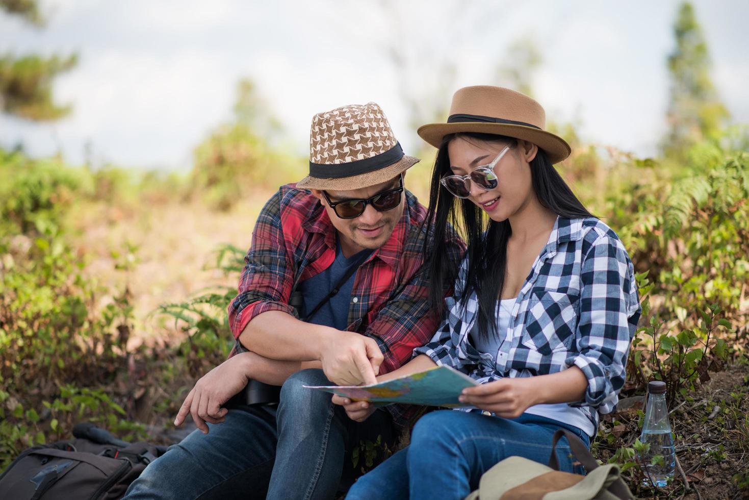 Young couple looking at map while hiking in the forest photo