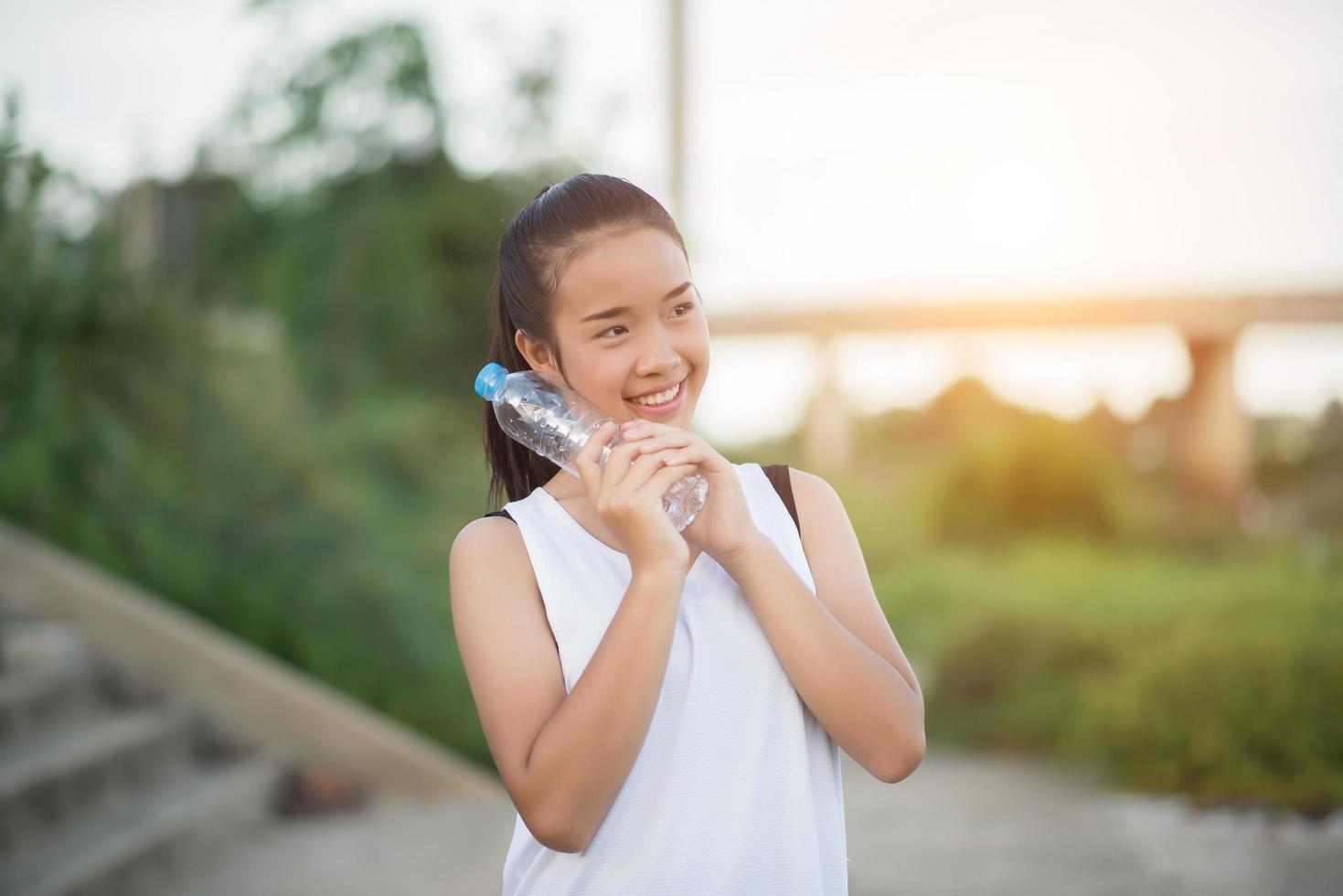 Joven adolescente fitness sosteniendo una botella de agua después de ejecutar el ejercicio foto