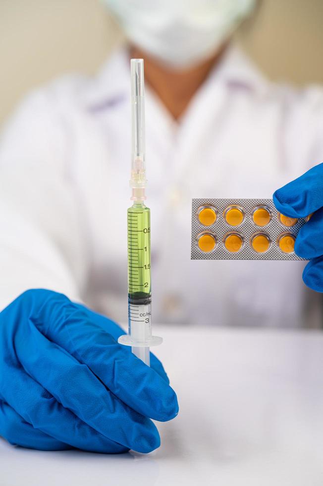 Scientist wearing gloves holding a syringe with a vaccine to prevent covid-19 photo