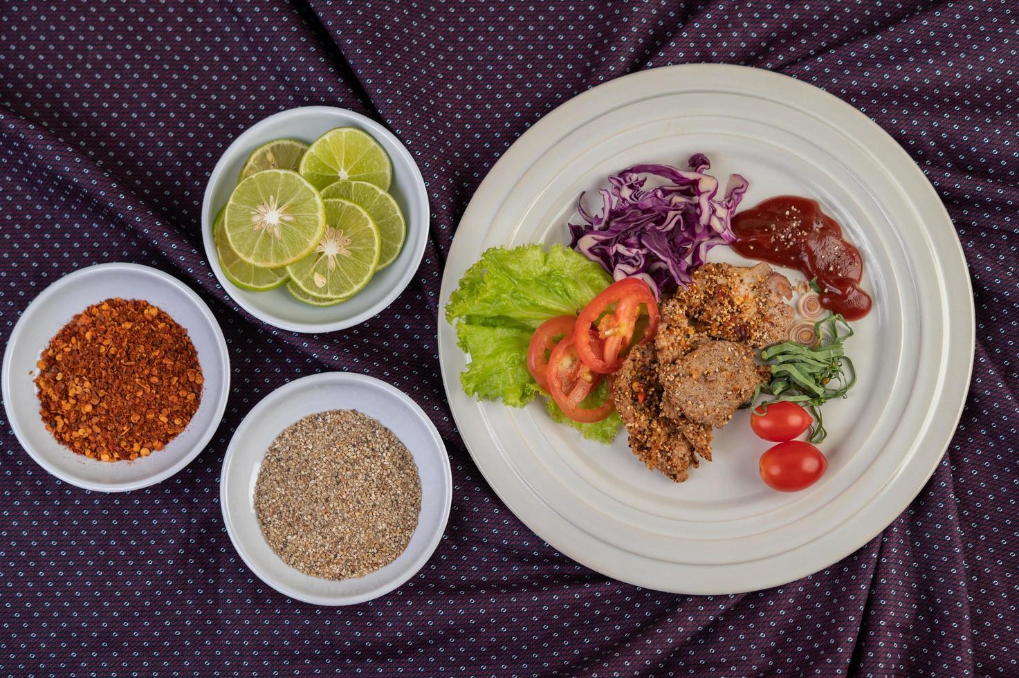 Plated pork salad with peppers, tomato, lemon, lime, garlic and salad photo