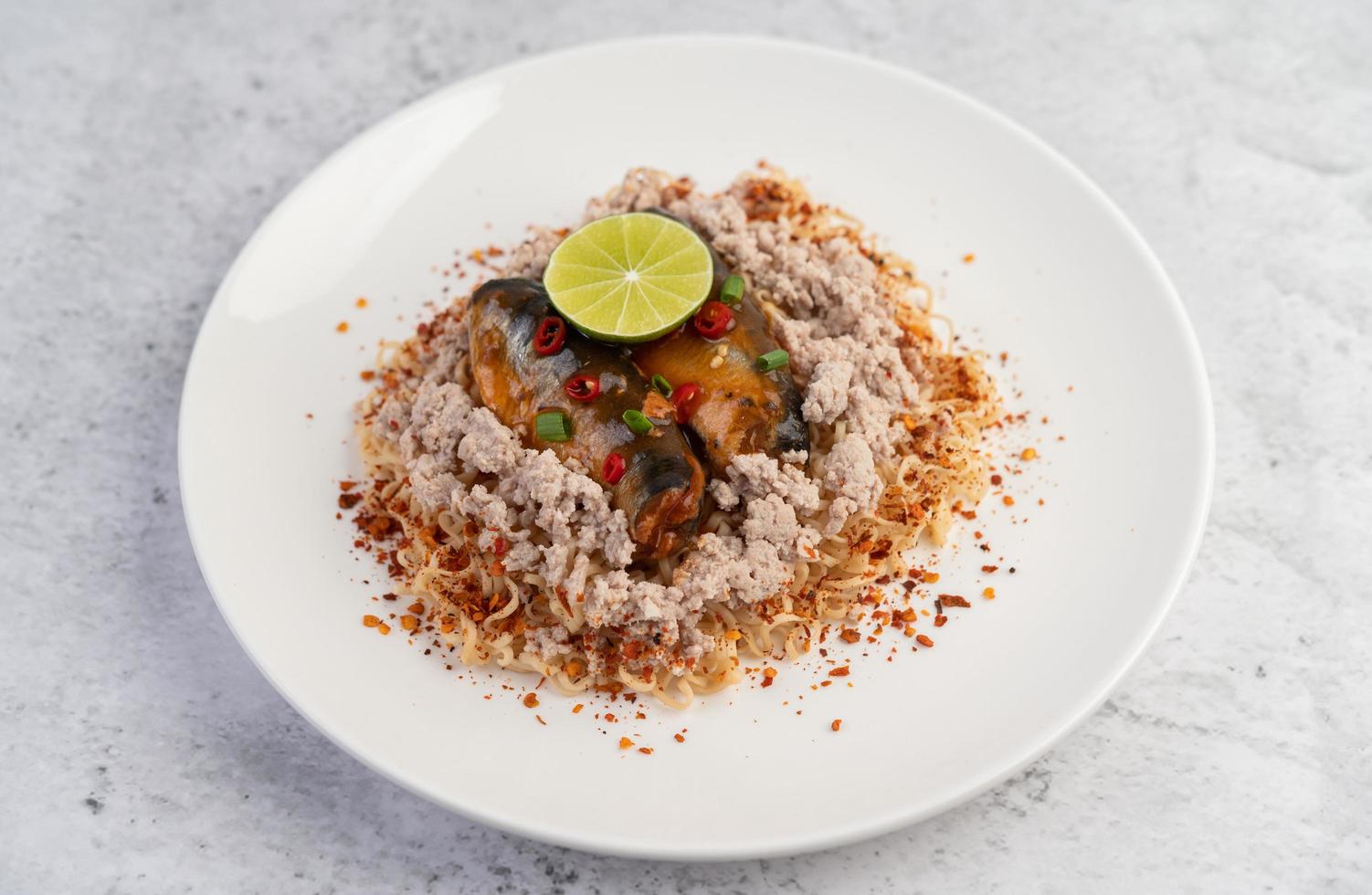 fideos cubiertos con carne de cerdo picada, pescado enlatado y limón foto