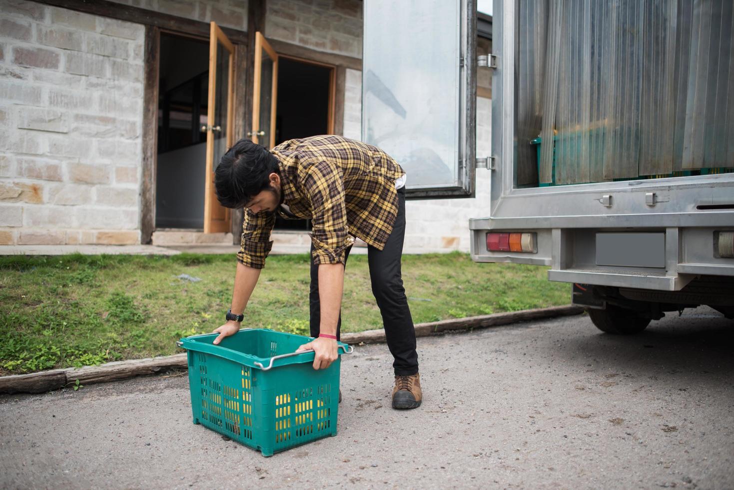 Retrato de un agricultor hipster sosteniendo una caja de frutas para la venta en el mercado foto