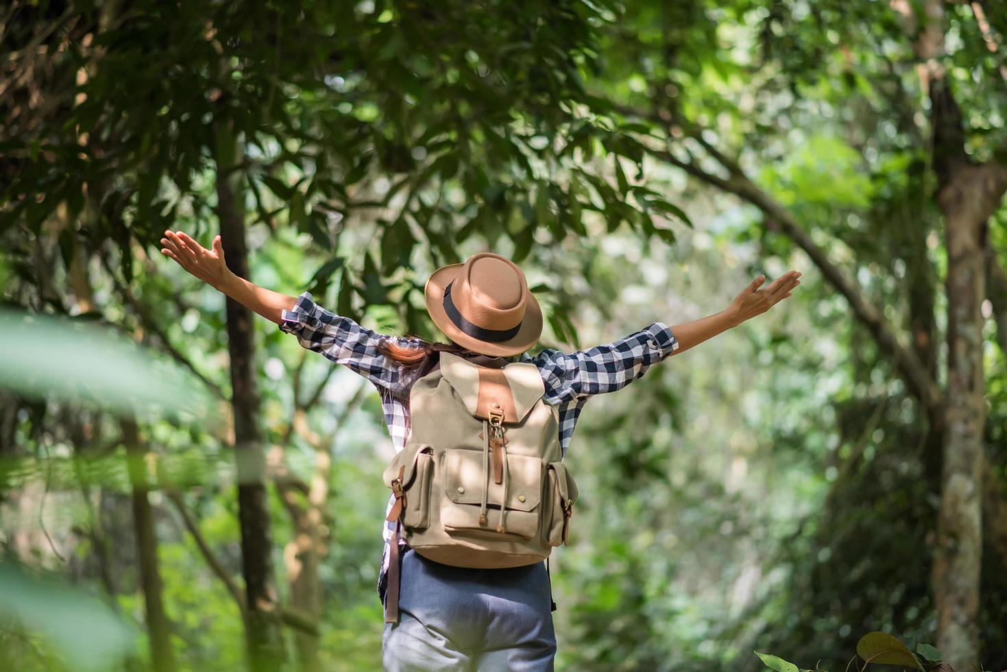 Happy young woman raising her arms to greet the sun in the forest photo