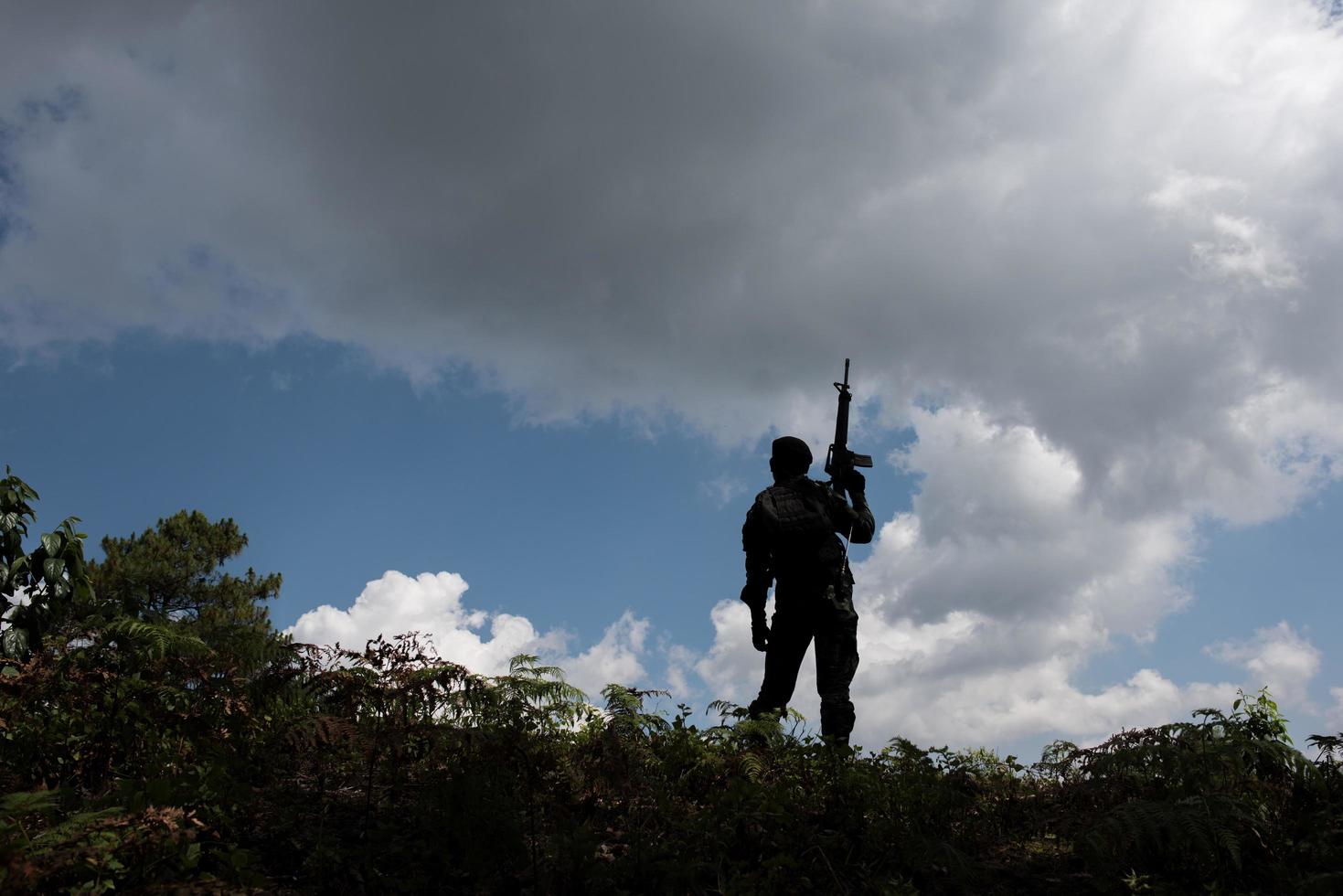 Military silhouettes of soldiers with readied weapon photo