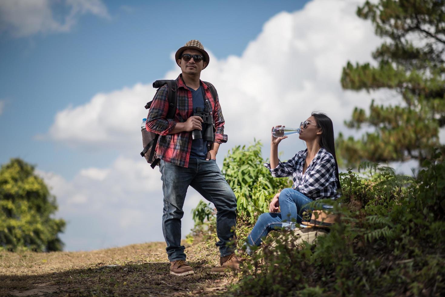 Young couple looking at map while hiking in the forest photo