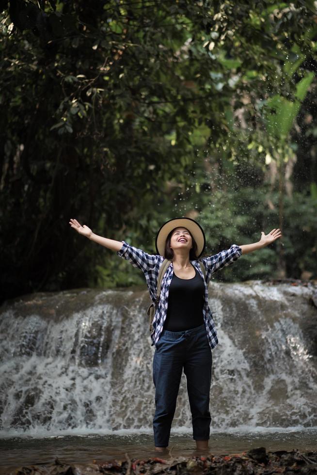 Young woman having fun under a waterfall in the forest photo