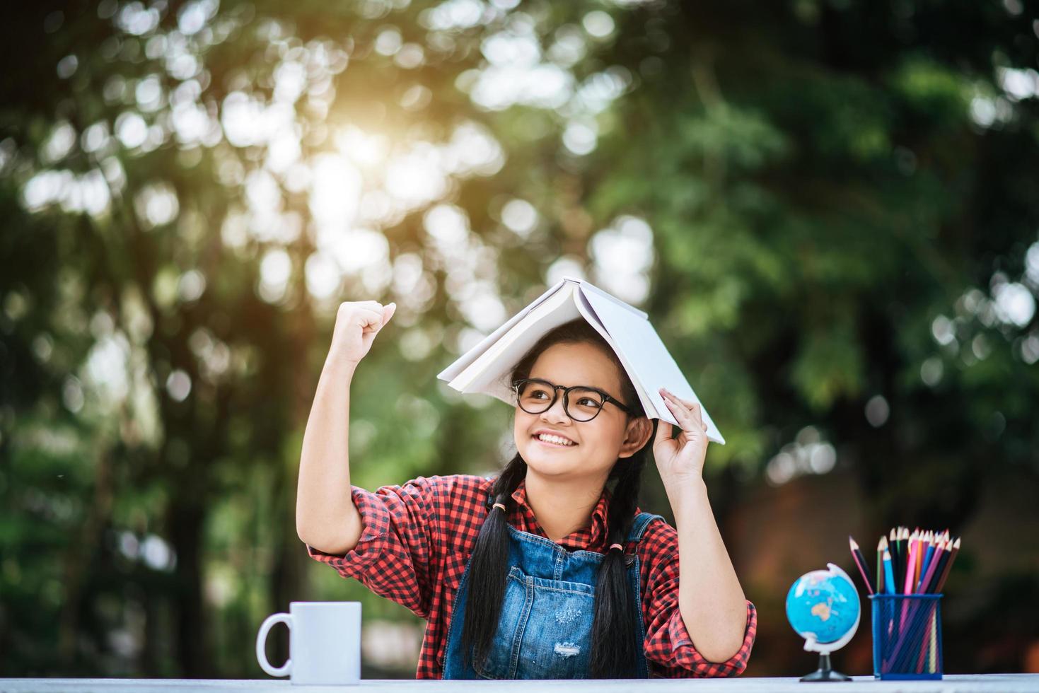 Young girl with book over her head in the park photo