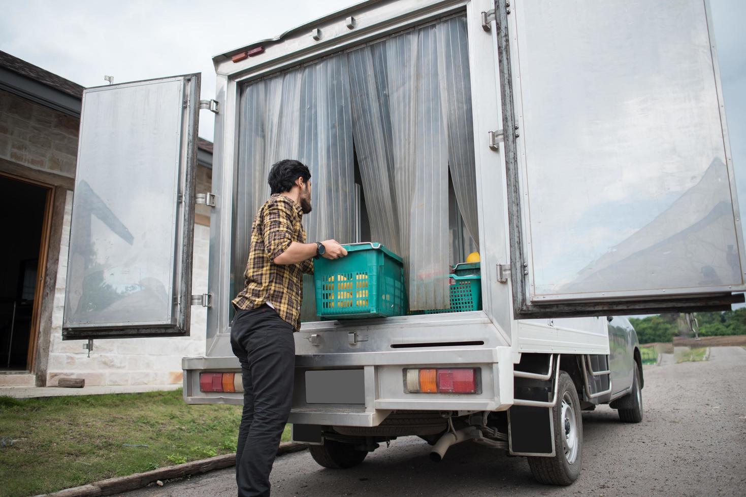 Portrait of a hipster farmer holding box of fruit for market sale photo