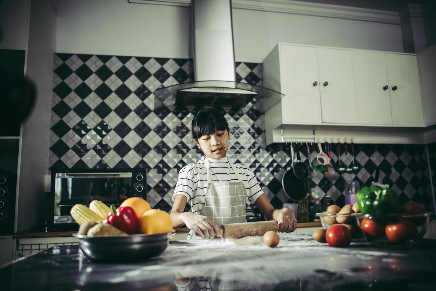 Little chef using rolling pin stretching the dough photo