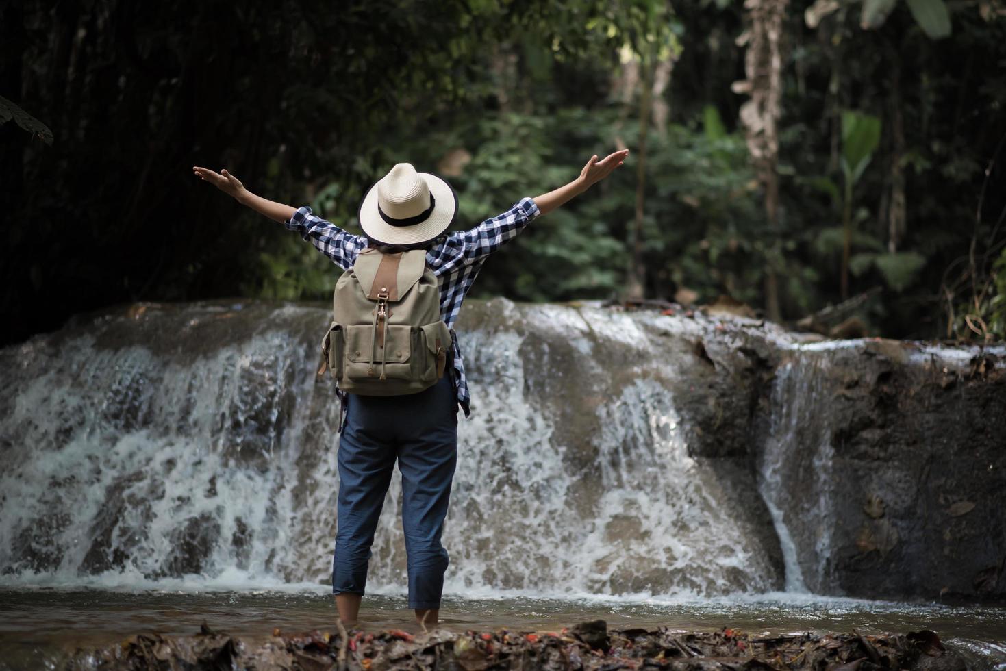 Young woman having fun under a waterfall in the forest photo