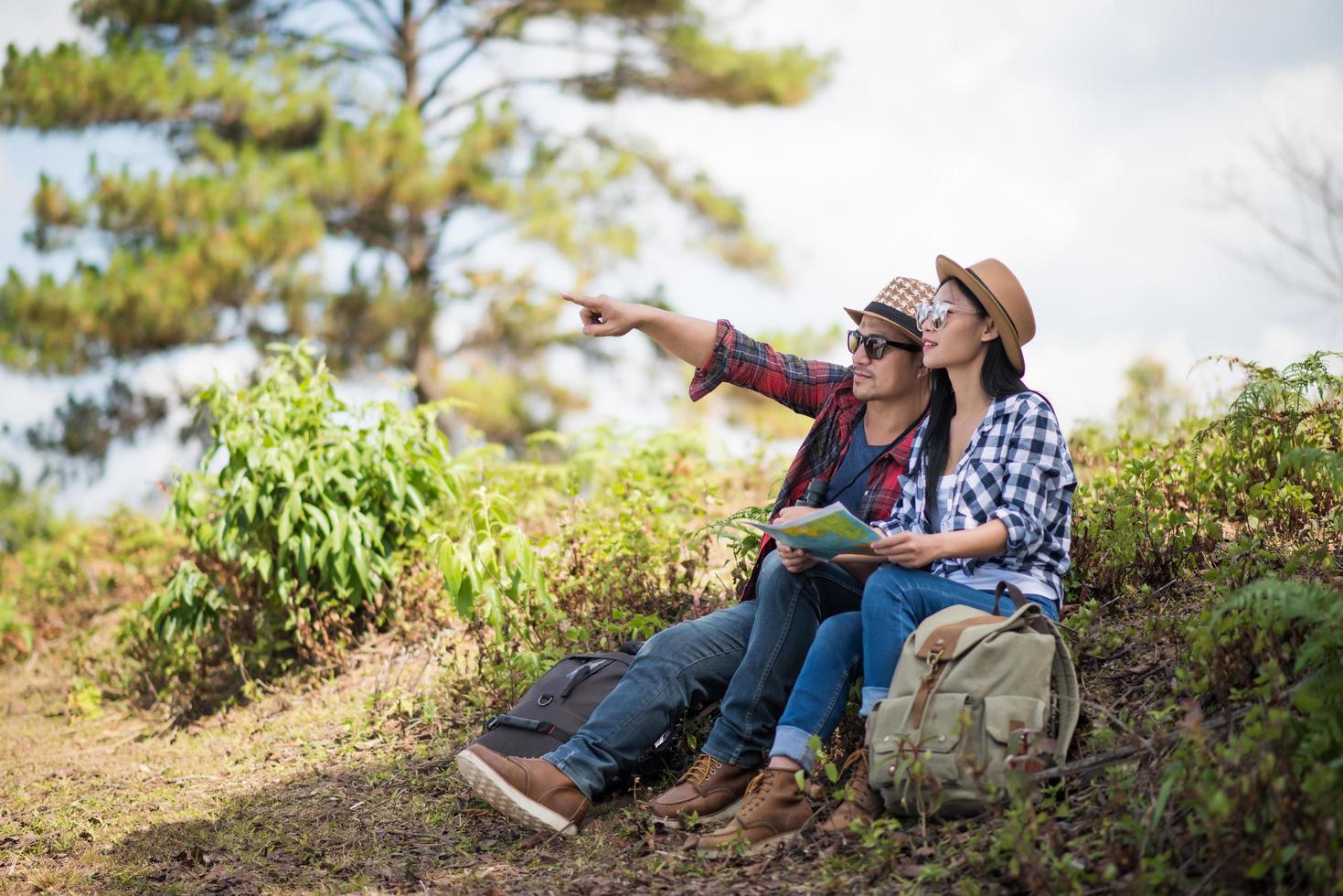 Young couple looking at map while hiking in the forest photo