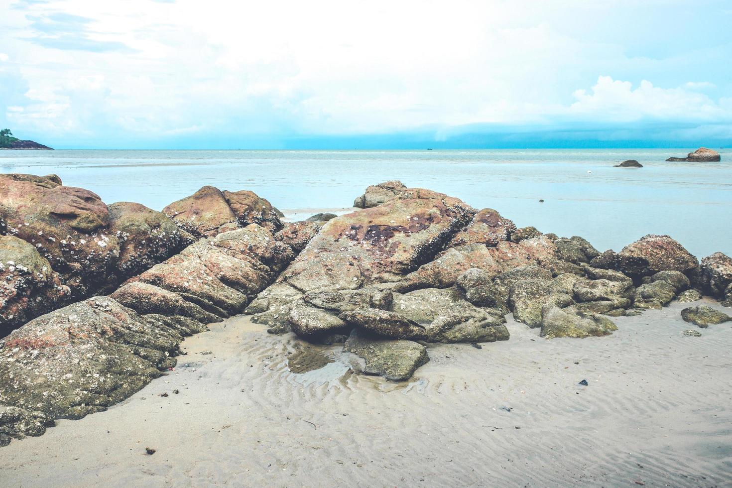 Rocks on beach with cloudy blue sky photo