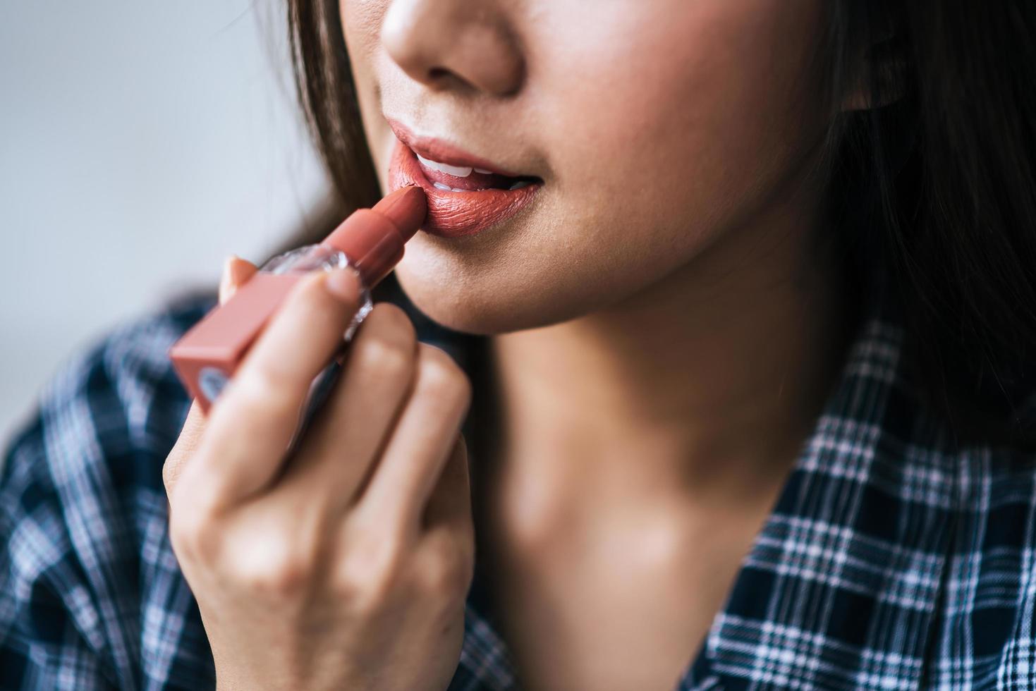 Close-up portrait of a woman putting on lipstick photo